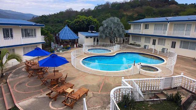Piscinas de Hotel Cabaleón con parasoles azules, asoleadoras y montañas al fondo en Tena, Cundinamarca